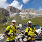 Mountain biking in South Tyrol © Hotel Jonathan Two cyclists in yellow jerseys with mountain and parked cars behind