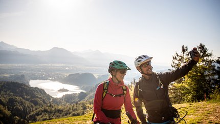 Into the Wild: Mountainbiken in Slowenien © Bled - Samo Vidic Zwei Fahrradfahrer machen Selfie mit Berg- und Seeblick im Hintergrund
