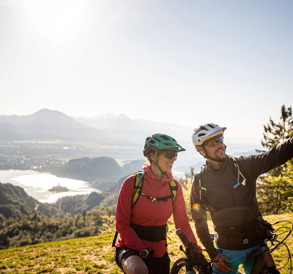 Zwei Fahrradfahrer machen Selfie mit Berg- und Seeblick im Hintergrund