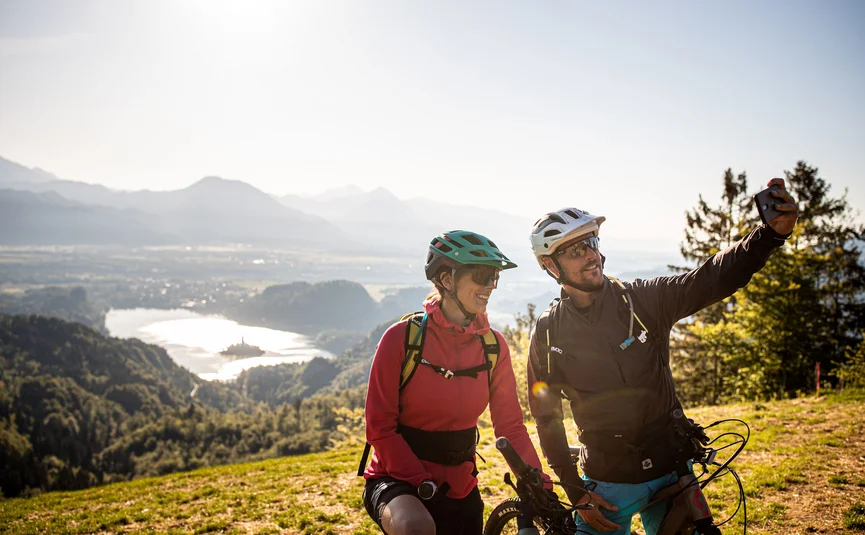 Mountainbike Urlaub in den Julischen Alpen © Bled - Samo Vidic Zwei Fahrradfahrer machen Selfie mit Berg- und Seeblick im Hintergrund