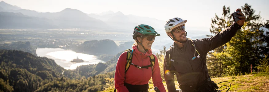 Dein Julische Alpen-Guide © Bled - Samo Vidic Zwei Fahrradfahrer machen Selfie mit Berg- und Seeblick im Hintergrund