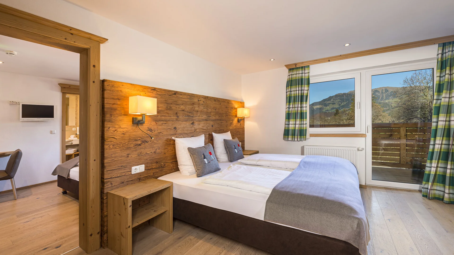 Hell eingerichtetes Schlafzimmer mit Doppelbett und Blick auf Berge