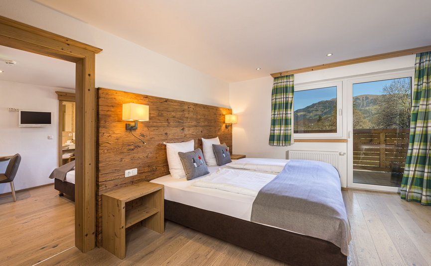 Hell eingerichtetes Schlafzimmer mit Doppelbett und Blick auf Berge