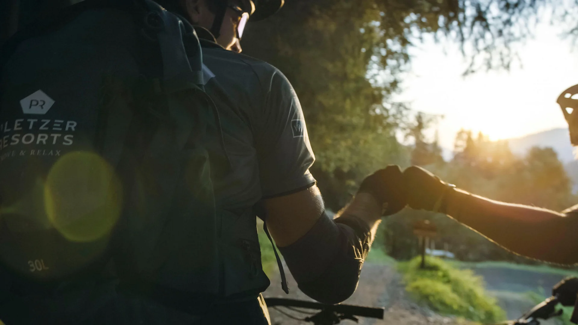 Zwei Radfahrer geben sich beim Sonnenuntergang die Faust ab
