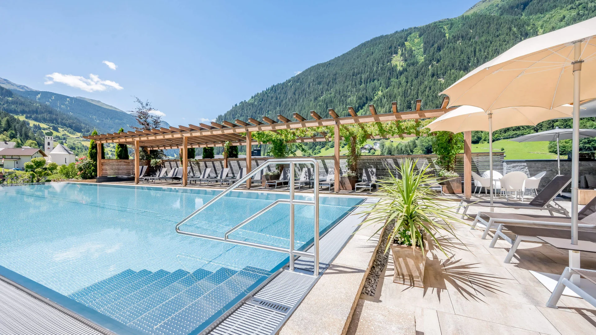 Schöner Swimmingpool mit Bergen und Sonnenliegen bei klarem Wetter
