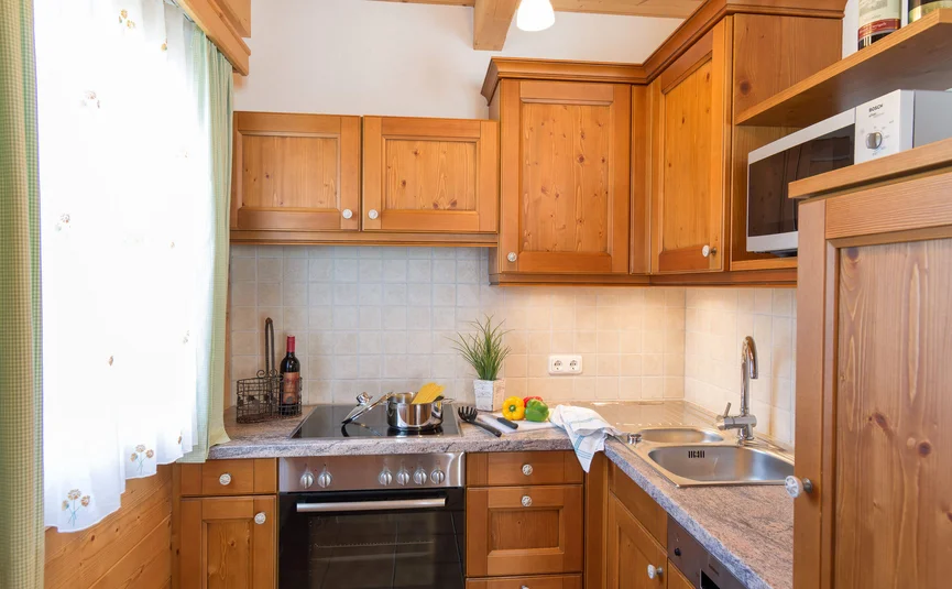 Kleine houten keuken met fornuis, gootsteen, magnetron en werkblad