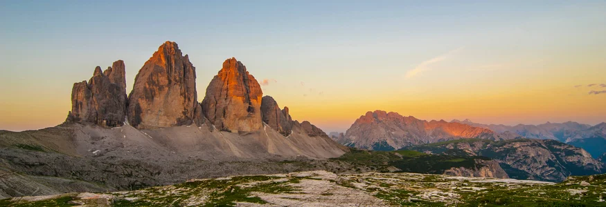 Drei Zinnen im Sonnenuntergang mit grüner Bergwiese im Vordergrund