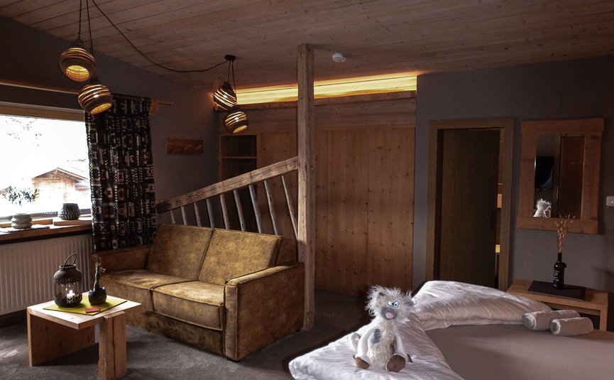 Gemütliches Holzzimmer mit Sofa, Bett und dekorativem Stofftier auf der Bettdecke