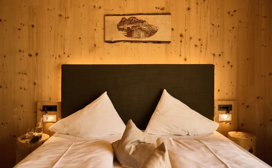 HIRBEN Naturlaub **** © David Rasche Cozy double bed with white pillows and wooden wall background
