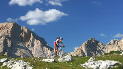 Mountain biker riding on rocky mountain trail under clear sky