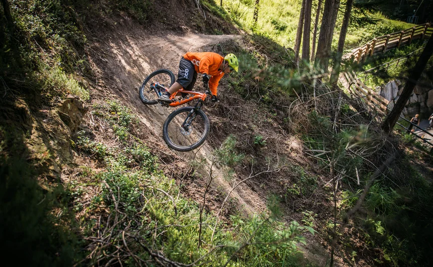 Mountainbiker fährt eine steile Schlammstrecke im Wald hinab