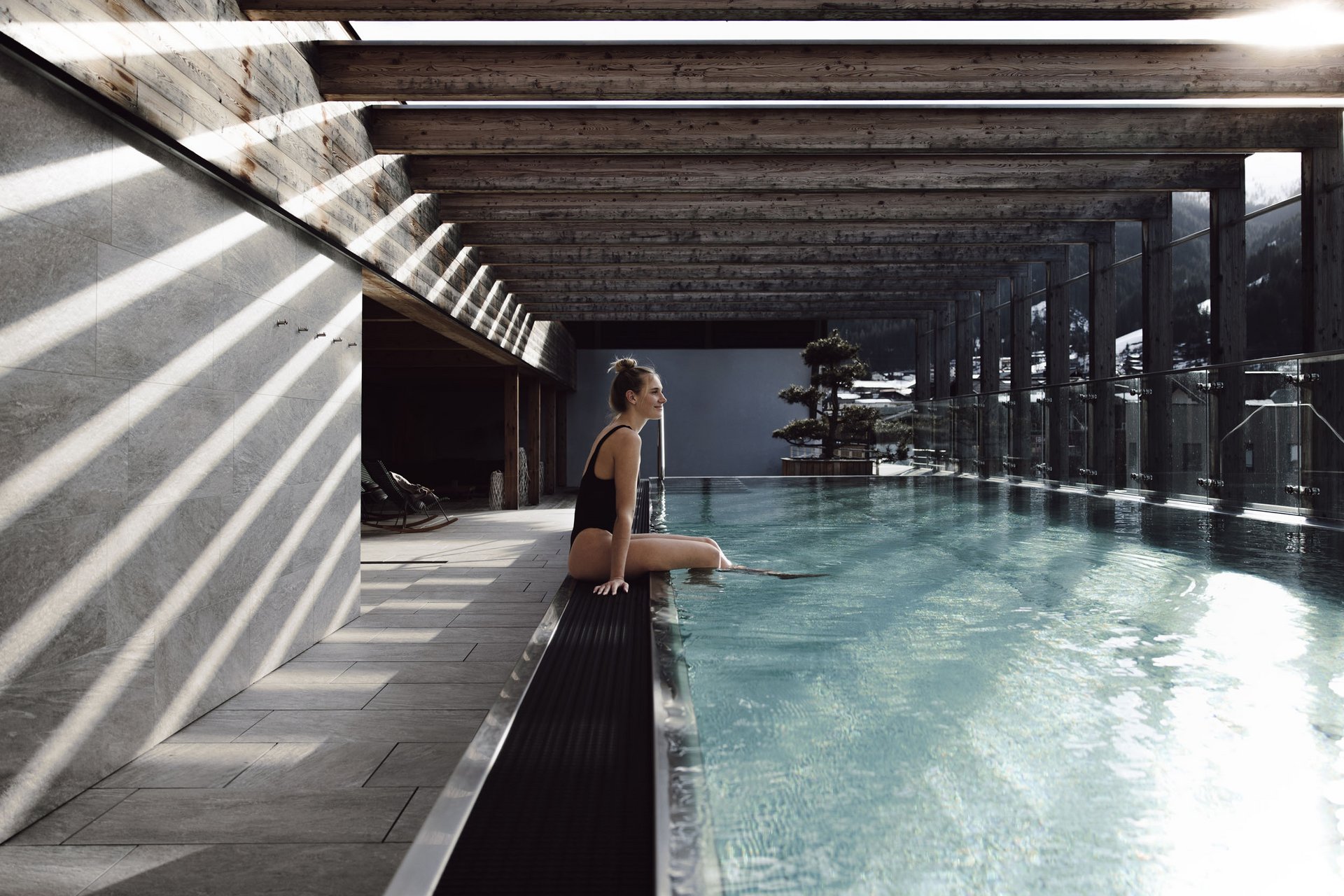 Frau am beheizten Pool mit Holzbalkendecke und Bergblick