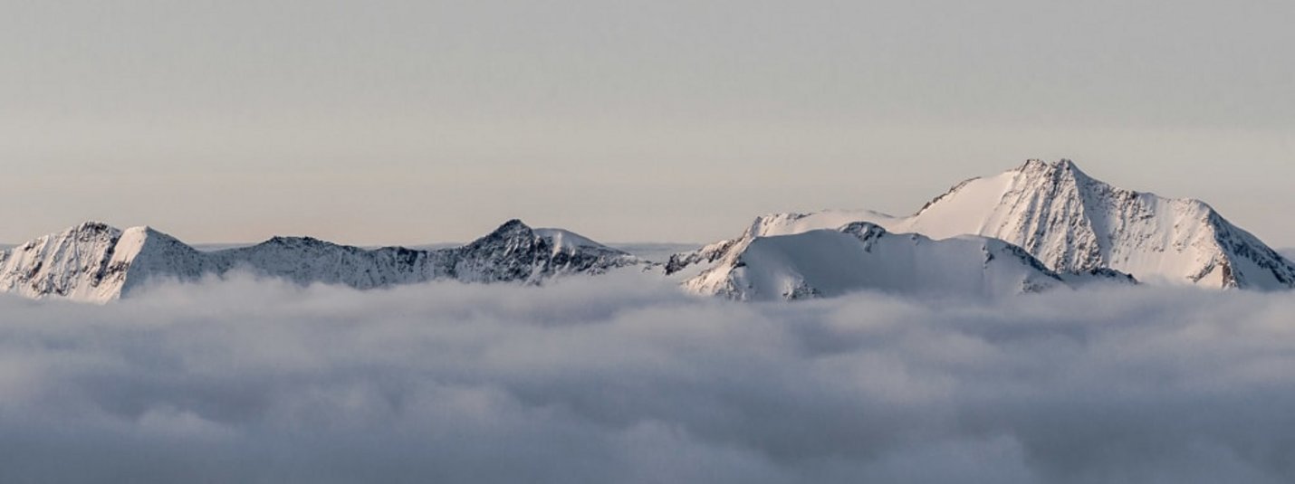 Snow-covered mountain peaks above a thick cloud layer