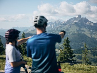 Two cyclists looking at mountain panorama in the Alps on a sunny day