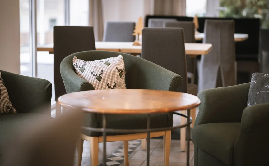Hotel Innerhofer *** © Lunah Photo & Design Gemütliche grüne Sessel mit Hirschkissen um einen runden Holztisch in einem Restaurant