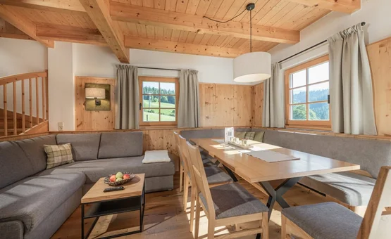 Mid Week 4 Nächte Gemütlicher Wohn- und Essbereich mit Holzbalkendecke, Ecksofa und großen Fenstern mit Blick ins Grüne