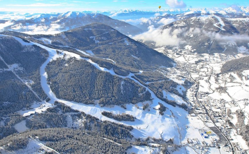 Aerial view of snowy ski resort in mountains under clear sky
