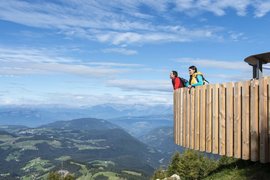 Zwei Wanderer auf einer Aussichtsplattform mit Blick auf Berge und Tal