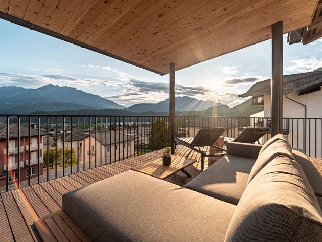 Terrasse mit Sofa, Liegestühlen und Blick auf Berge bei Sonnenuntergang