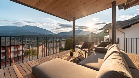 Terrasse mit Sofa, Liegestühlen und Blick auf Berge bei Sonnenuntergang