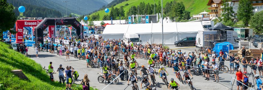 Mountainbike-Rennen in bergiger Landschaft mit Zuschauern und Teilnehmern