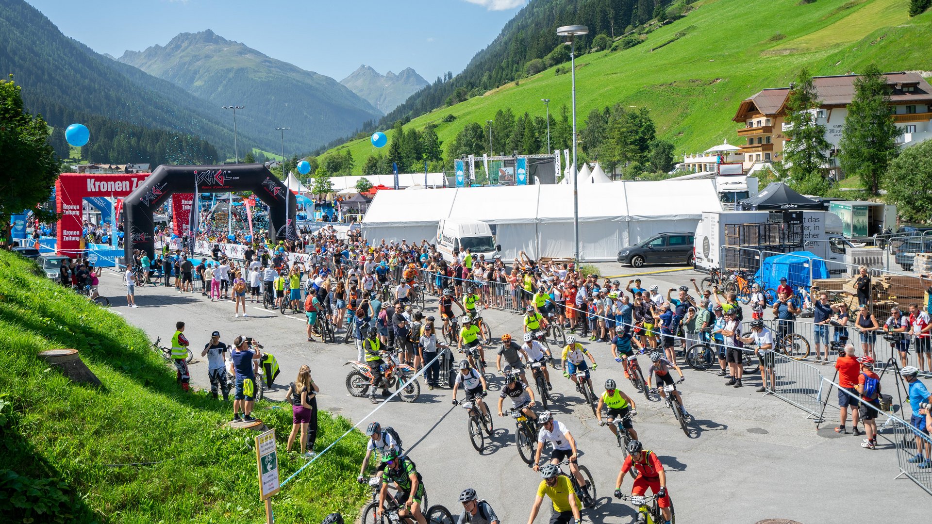 Mountainbike-Rennen in bergiger Landschaft mit Zuschauern und Teilnehmern