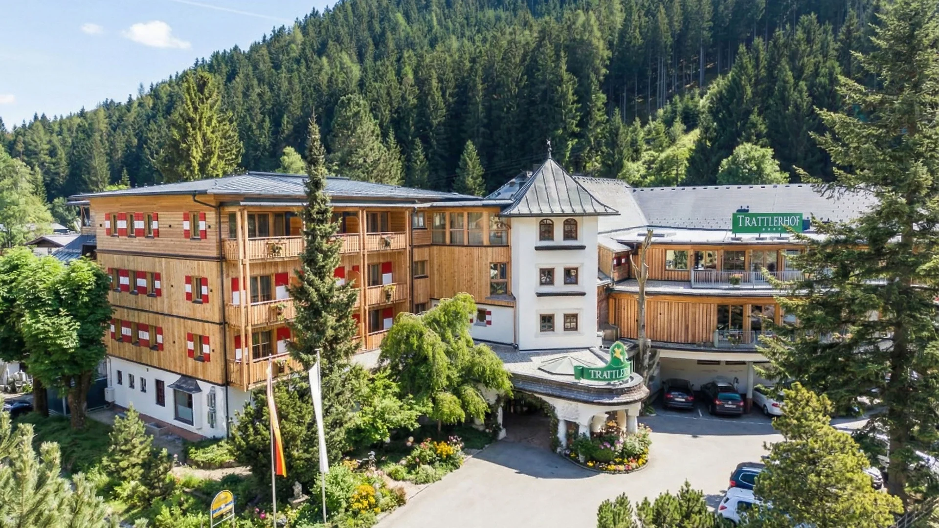 Hotel Trattlerhof umgeben von Bäumen und Bergen im Sommer