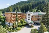 Hotel Trattlerhof umgeben von Bäumen und Bergen im Sommer