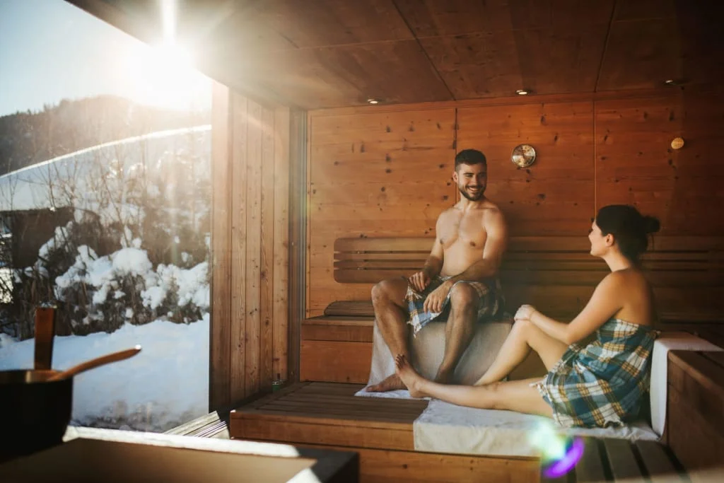 Paar entspannt in der Sauna mit Blick auf verschneite Berge
