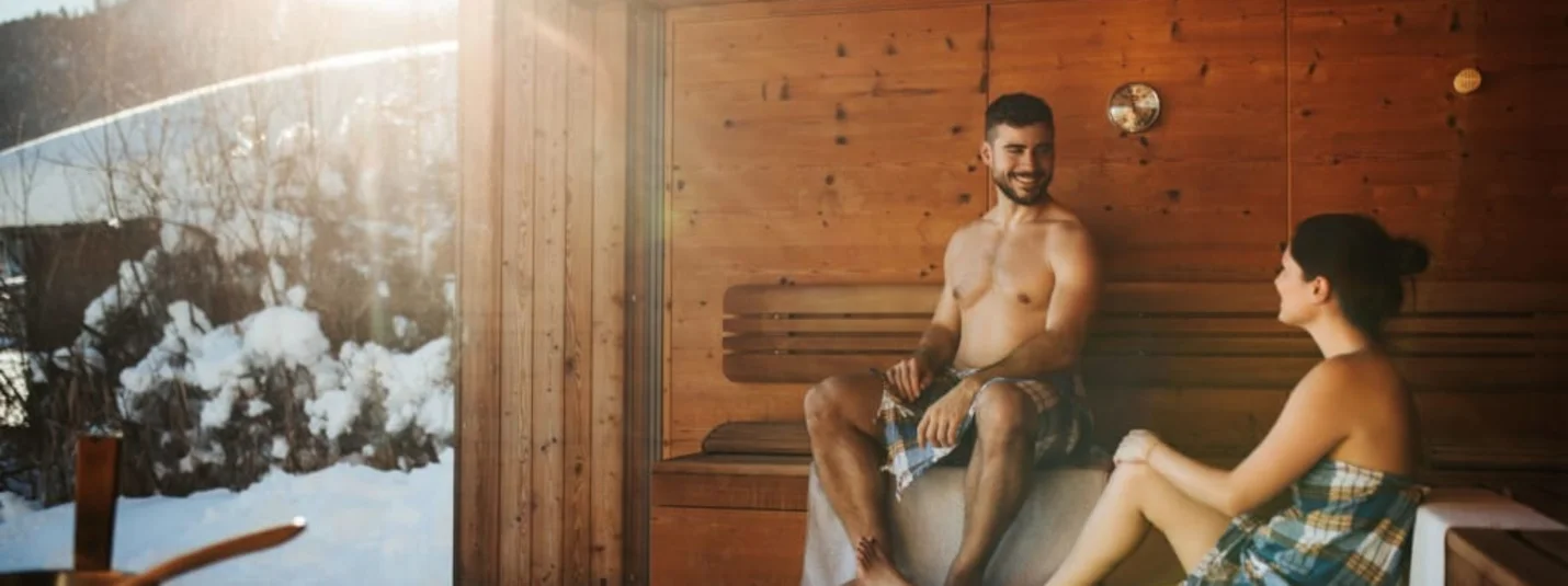 Paar entspannt in der Sauna mit Blick auf verschneite Berge