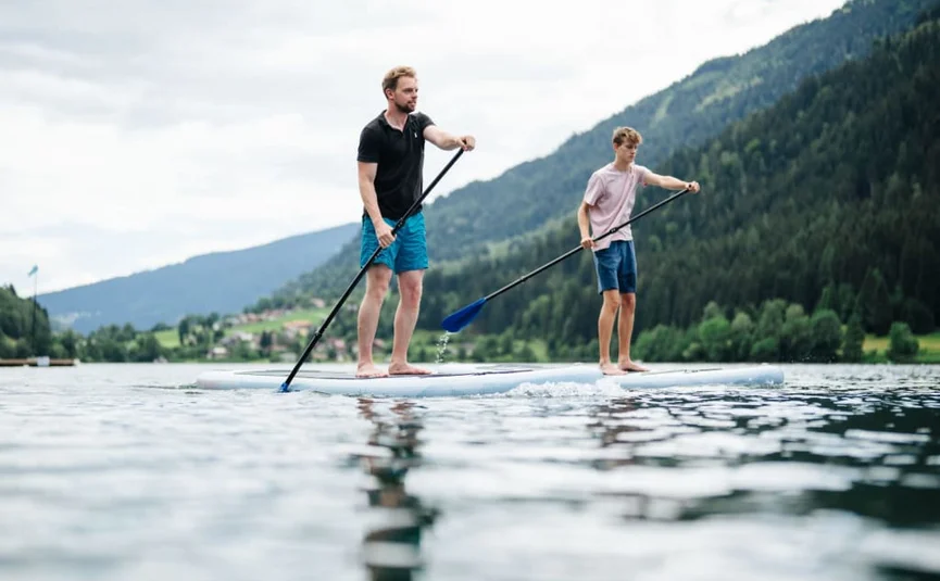Zwei Männer paddeln auf einem See mit Bergen im Hintergrund