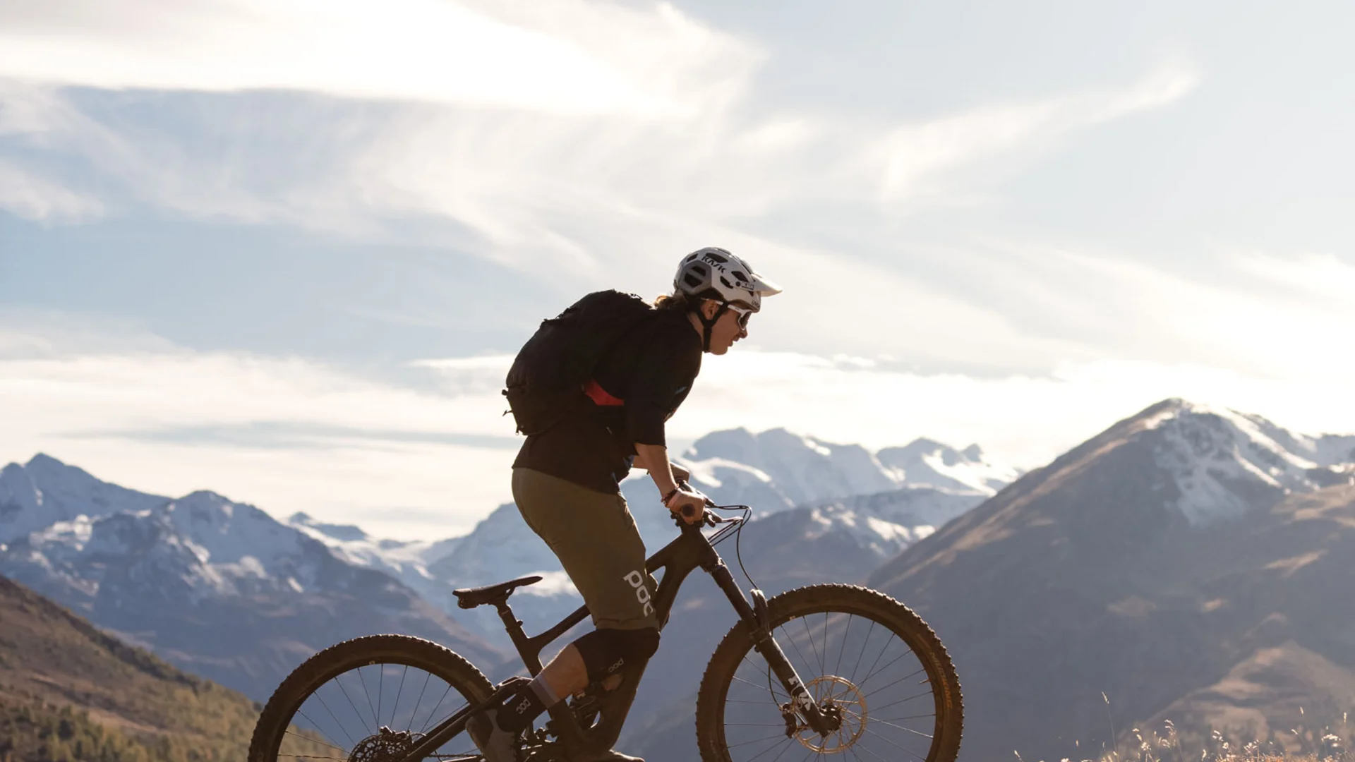 Mountainbiker fährt auf einem Hügel mit Bergpanorama bei klarem Himmel