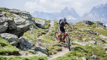 Mountain biker riding on narrow trail in rocky mountain landscape