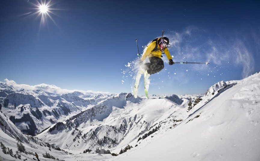 SKI OPENING Skier maakt sprong in zonnig besneeuwd berglandschap