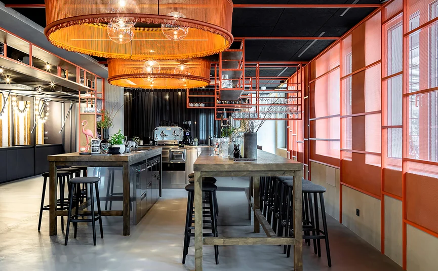 Modern bar with wooden tables, black stools, and orange lighting