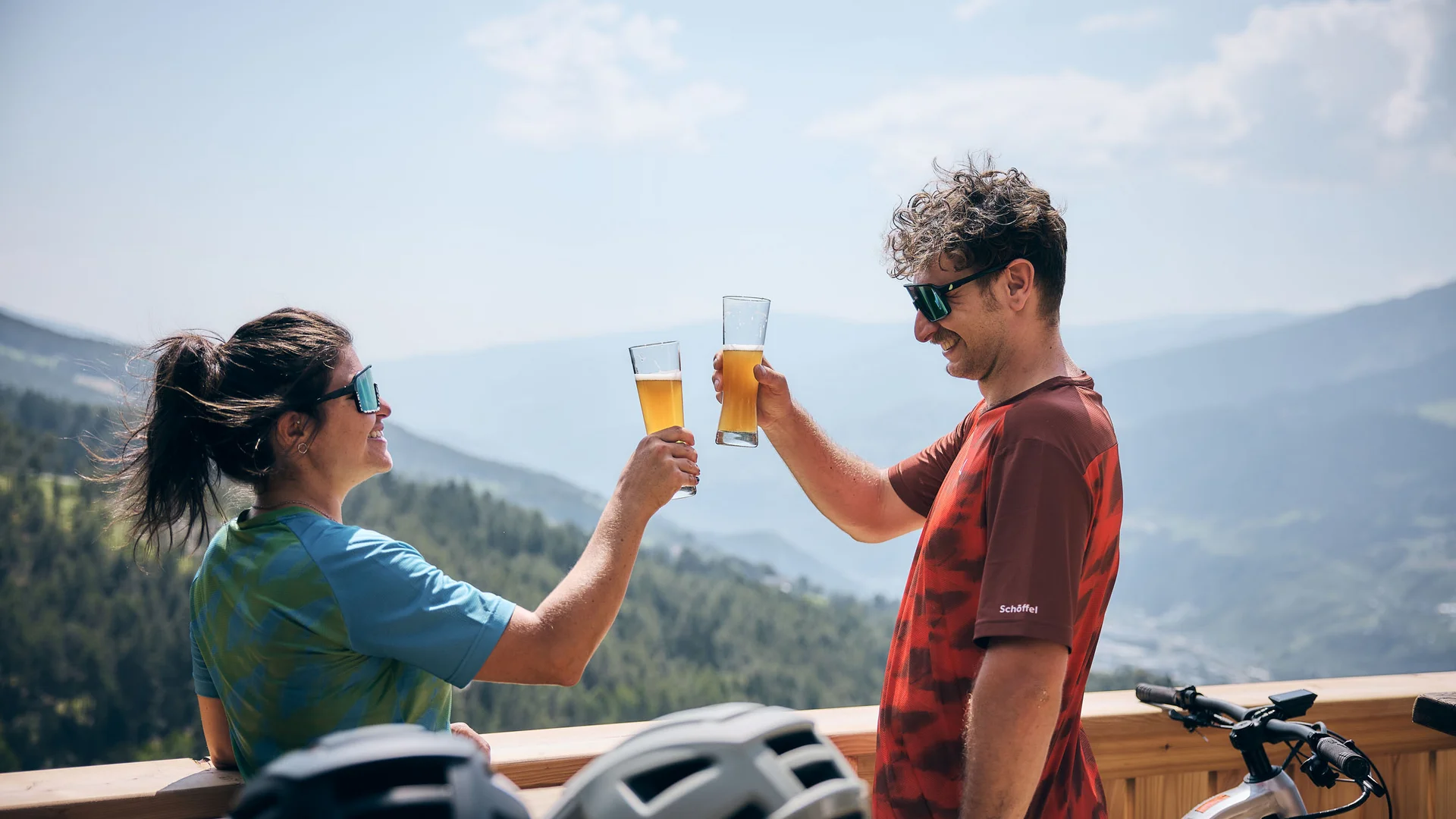 bike festa Südtirol in Brixen © Tobias Köhler Zwei Radfahrer stoßen mit Biergläsern auf einem Berg mit Panoramablick an