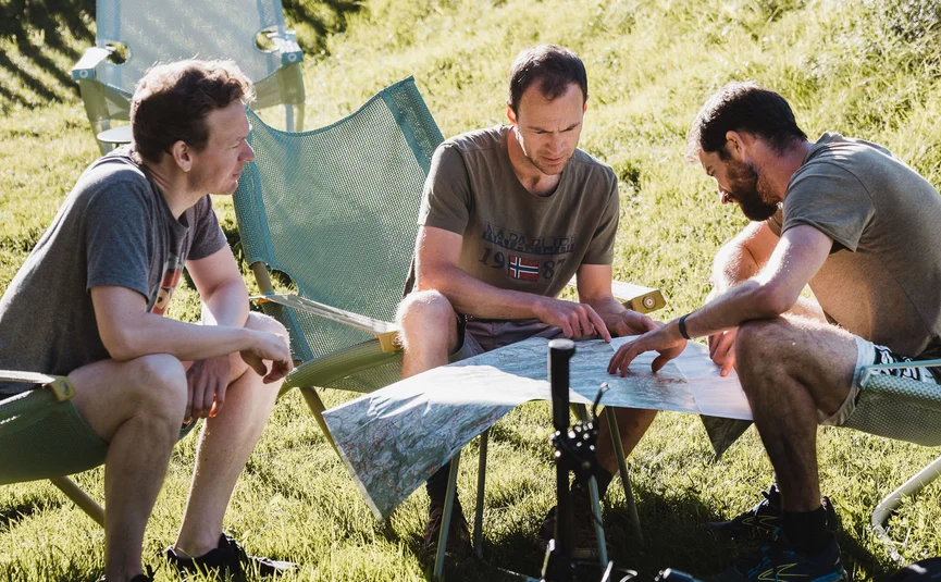 Drie mannen plannen een fietstocht met een kaart op het gras