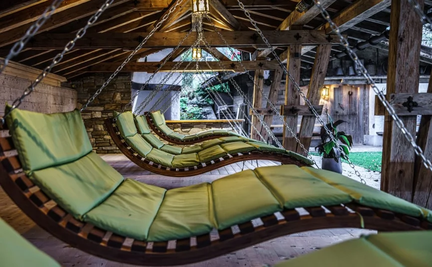 Hängende, grüne gepolsterte Liegestühle in einer Holzhütte