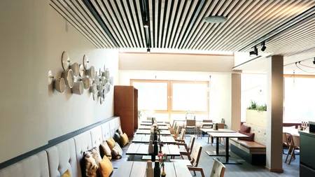 Best of Brandnertal © Klaus Andorfer Modernes Restaurant mit Holztischen, Stühlen und Wanddekoration aus weißen Schalen
