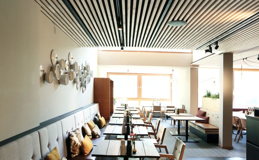 Modernes Restaurant mit Holztischen, Stühlen und Wanddekoration aus weißen Schalen