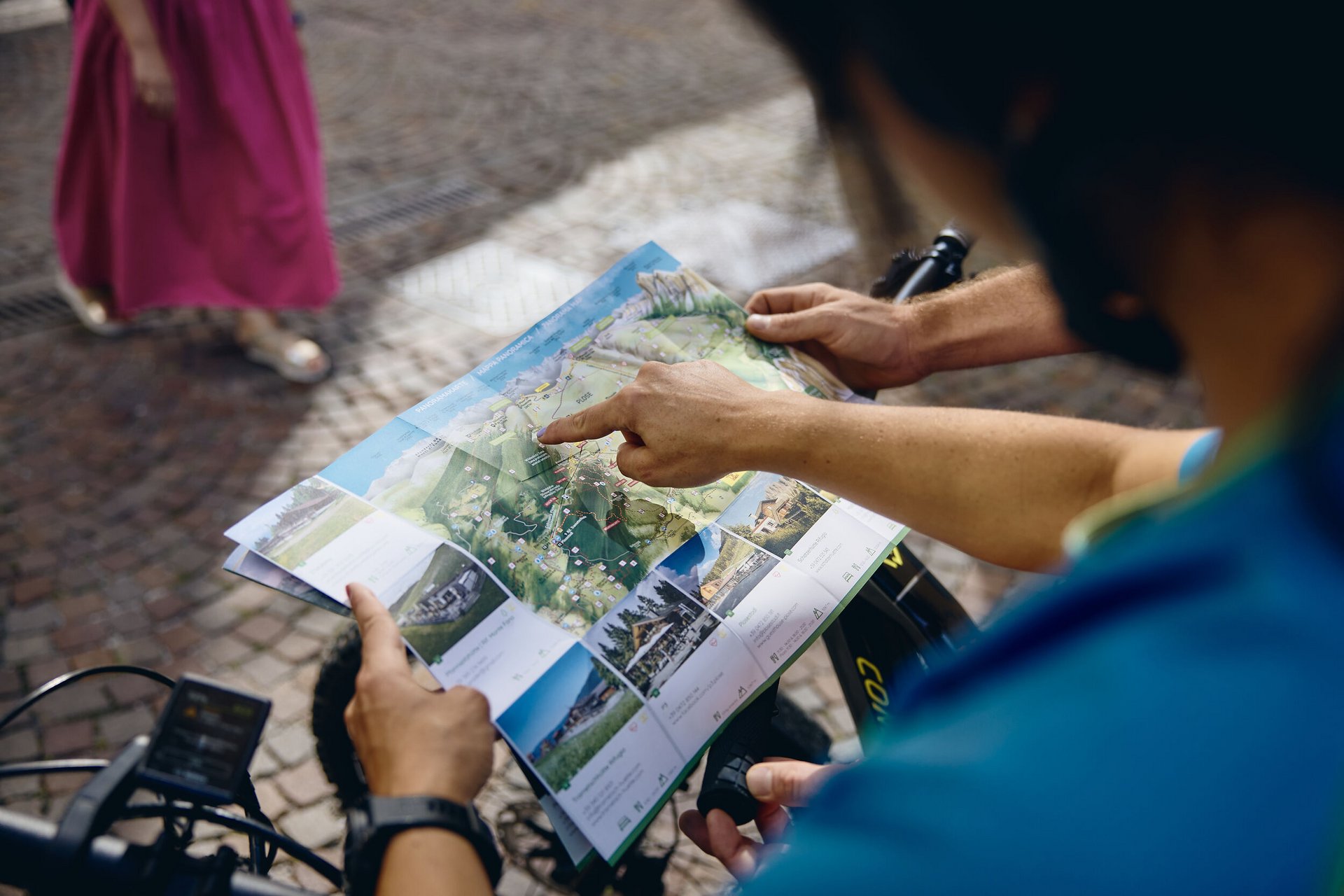 Person zeigt auf eine Landkarte beim Radfahren in einer Stadt