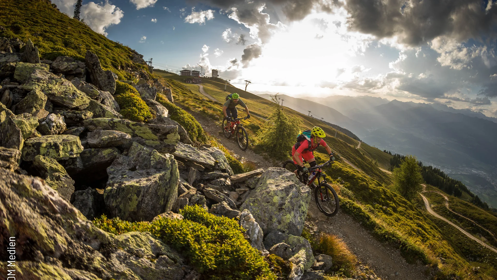 Zwei Mountainbiker fahren auf einem Bergpfad bei Sonnenuntergang