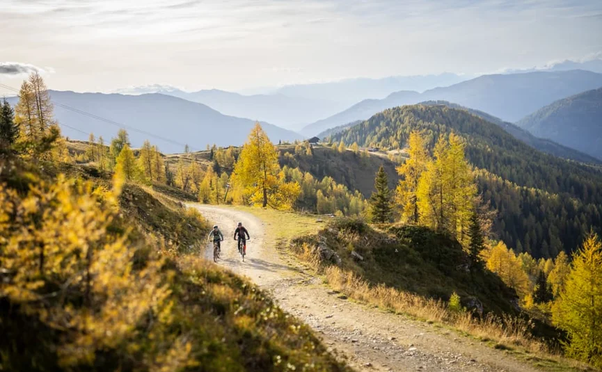 Twee fietsers op een pad in een herfstachtig berglandschap