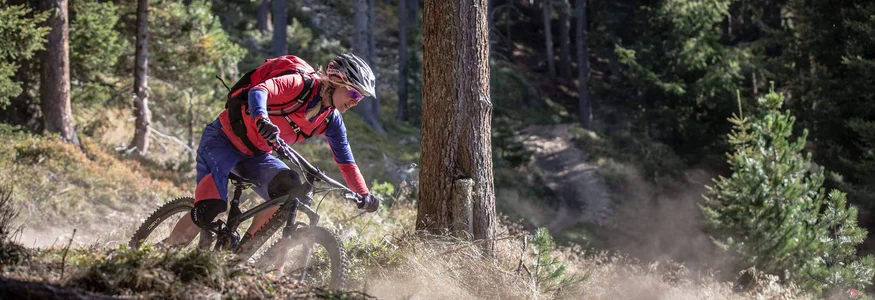 Mountainbiker fährt schnell auf Waldweg und wirbelt Staub auf