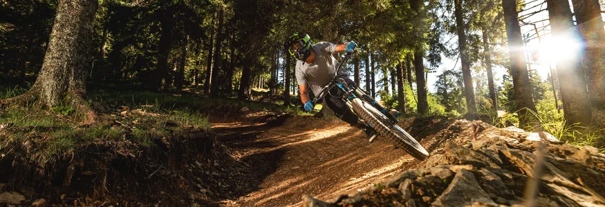Mountain biker riding on sunny forest trail with sharp turn