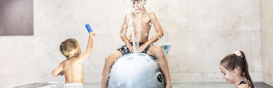 Zwergenwoche Drie kinderen spelen in zwembad met een walvis-waterfontein