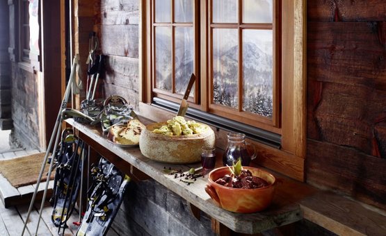 Schneeschuhe und winterliche Speisen auf einem Holztisch in einer Berghütte