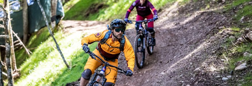 Zwei Mountainbiker fahren auf einem Waldpfad bergab