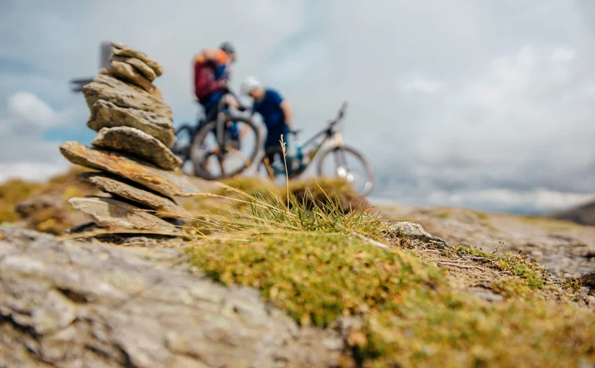 Stacked stones with two mountain bikers blurred in the background outdoors