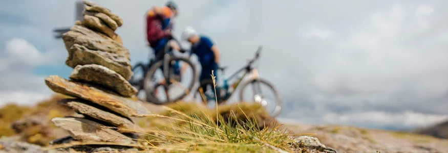 Gesteinsturm mit zwei Mountainbikern im Hintergrund in der Natur
